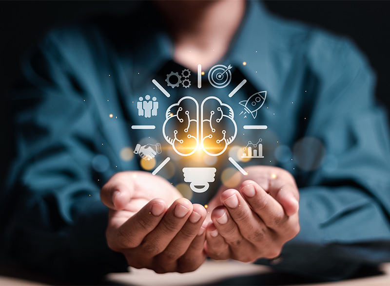 Glowing light bulb and brain with growth icons held in open hands